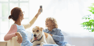 A woman operating the remote control for an air conditioning unit while seated on a couch with a child and a dog.