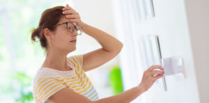 Woman feeling the heat of summer, turning down her AC